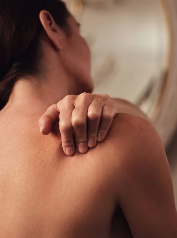 A woman holding her aching shoulder